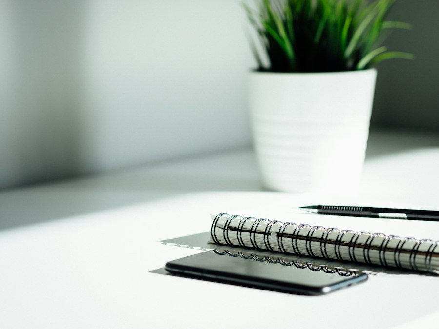 A notebook, pen, and phone on a sunlit desk, ready for planning.